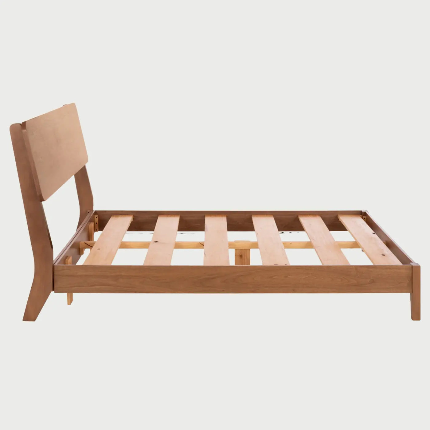 Vista de perfil de la cama Akari; destaca la esbeltez de su cabecera de madera y la continuidad del acabado nogal en los largueros laterales, ofreciendo una silueta limpia y moderna de inspiración japonesa.