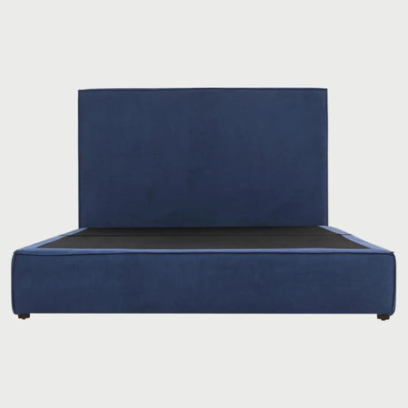 Vista frontal de la cama King Size Raquel; destaca por su cabecera extra ancha y rectangular tapizada en tela azul profundo, integrada a una base de perfil bajo que proyecta un diseño de bloque sólido y minimalista.