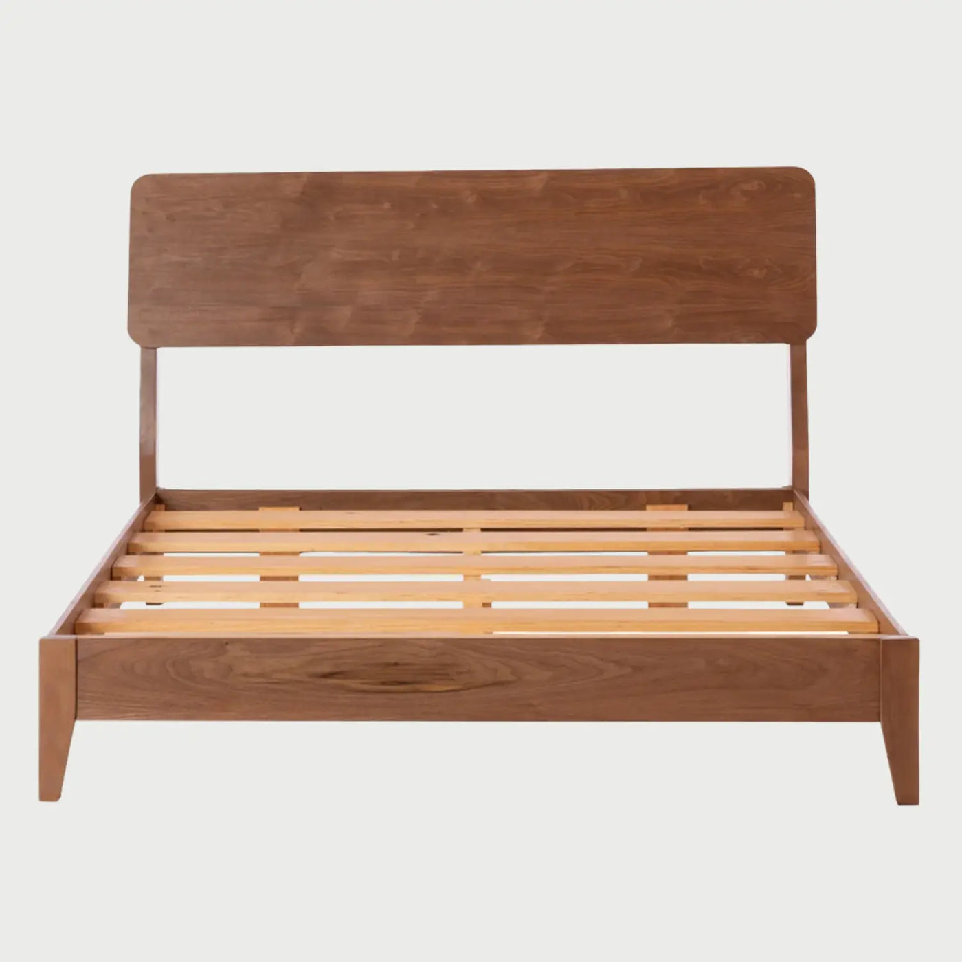 Vista frontal de la cama Queen Size Akari; presenta una estructura de madera con acabado nogal color café que incluye una cabecera rectangular de bordes redondeados y una base de perfil bajo con patas angulares sutiles.