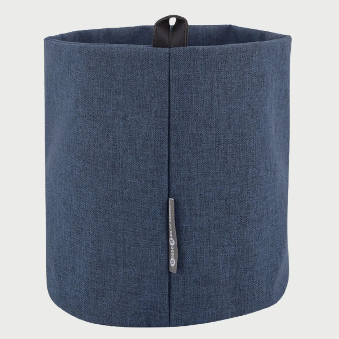 Vista trasera del cesto Melquiar mediano en color azul; presenta un cuerpo cilíndrico de tela flexible con una costura vertical central reforzada, una pequeña etiqueta lateral y un asa de cuero oscuro en el borde superior para facilitar su manejo.