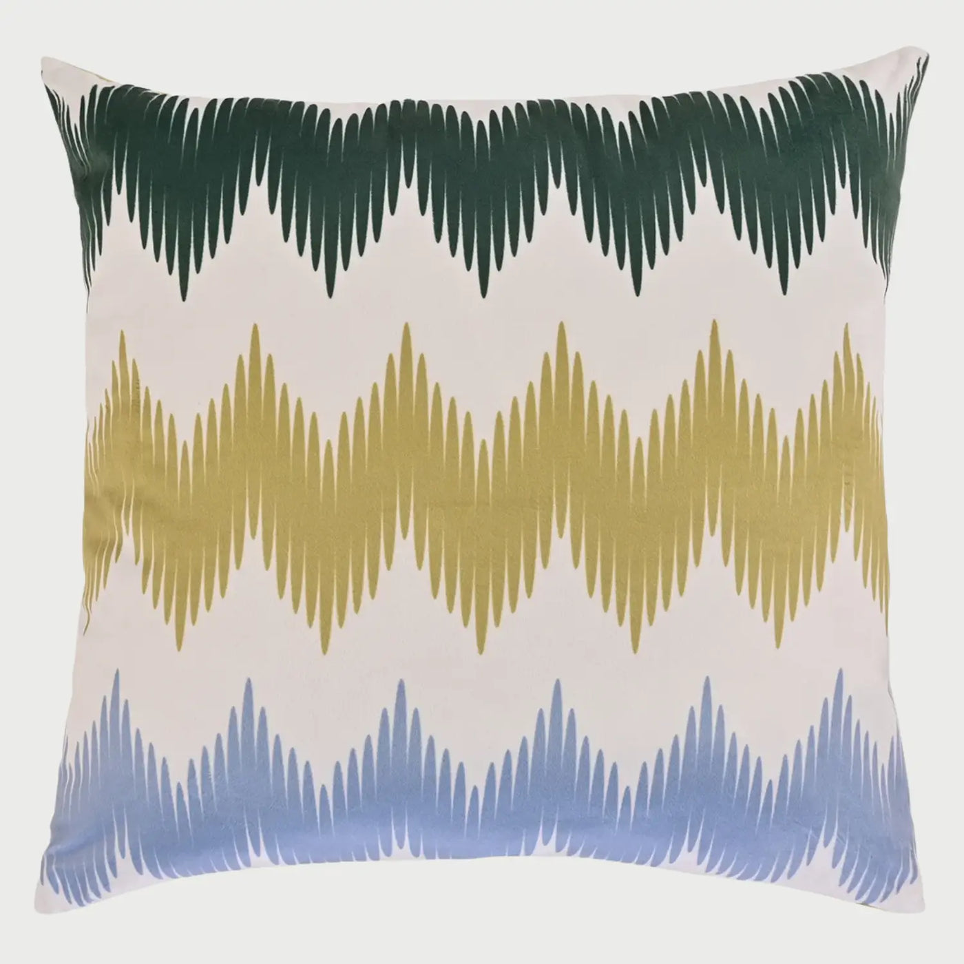 Vista frontal del cojín cuadrado Bohemio de 50 x 50 cm; presenta un diseño de tres franjas horizontales con un patrón de zigzag o puntas de flecha en colores verde bosque, mostaza y azul cielo sobre un fondo blanco, evocando un estilo artesanal y dinámico.