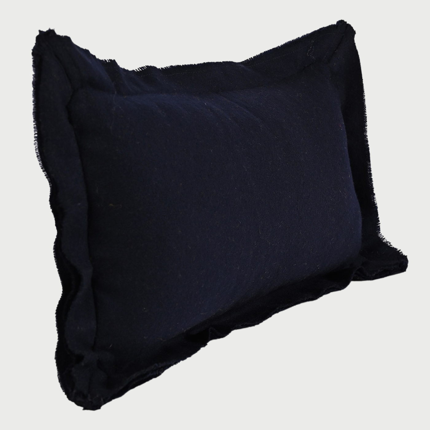 Vista lateral del cojín Céfiro azul; se aprecia el relieve de la pestaña desflecada y el volumen del relleno que proporciona un soporte lumbar firme, resaltando la densidad y calidez de la fibra de lana.