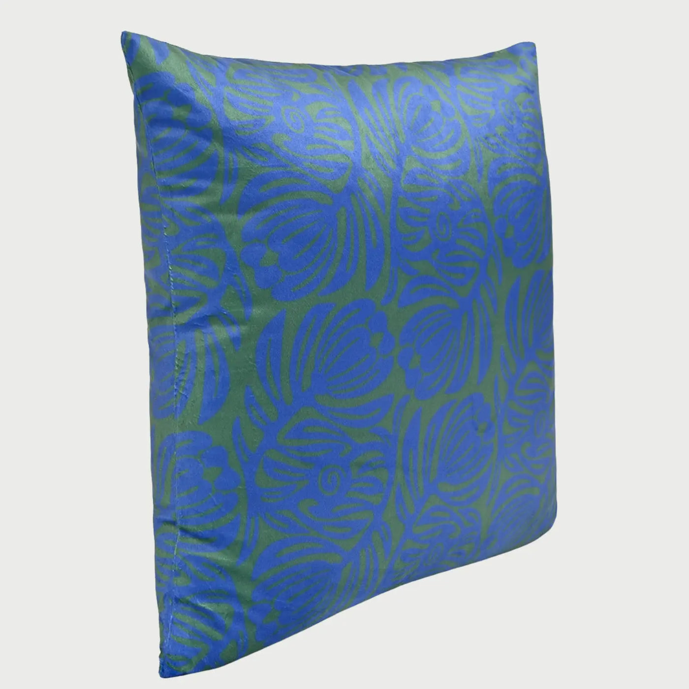 Vista lateral en perspectiva del cojín cuadrado Disco de 50 x 50 cm; muestra un volumen acolchado firme y un diseño de hojas o flores abstractas en color azul rey sobre un fondo verde bosque, confeccionado en una tela de terciopelo con brillo sutil.