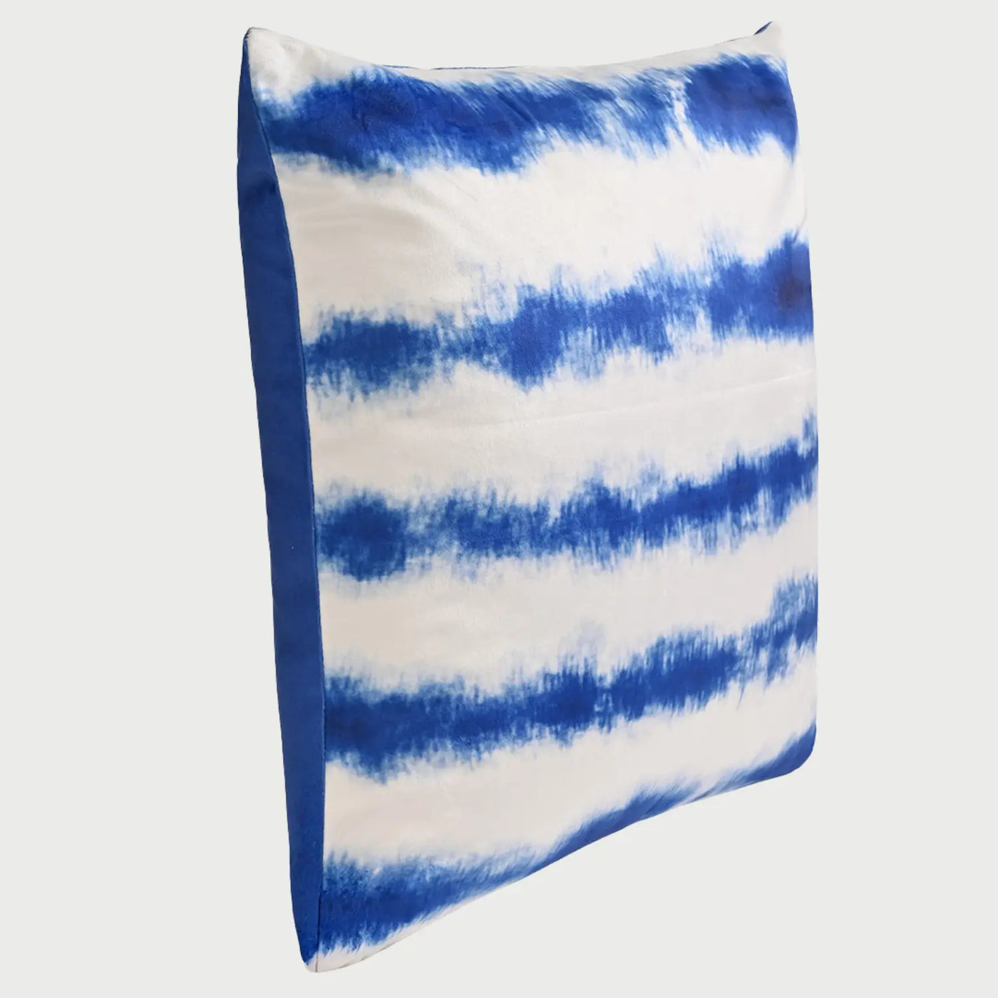 Vista lateral del cojín TieDye; se aprecia su perfil con un relleno generoso que le otorga un volumen mullido y firme, resaltando la suavidad del textil de terciopelo y la continuidad del efecto de teñido hacia los bordes de la pieza.