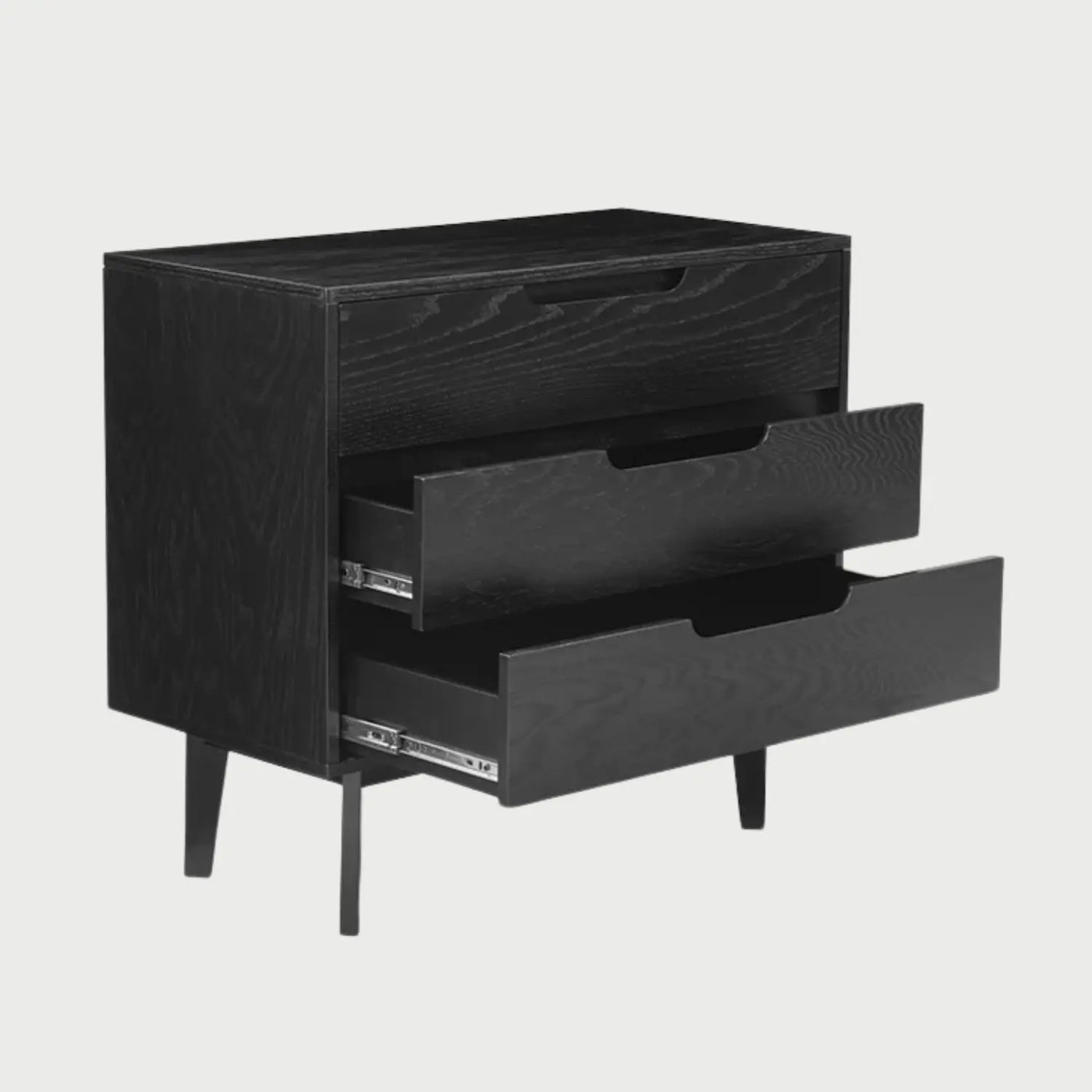 Vista lateral de la cómoda Talitha negra, mostrando el perfil rectangular profundo del cuerpo del mueble y la alineación perfecta de sus tres niveles de almacenamiento.
