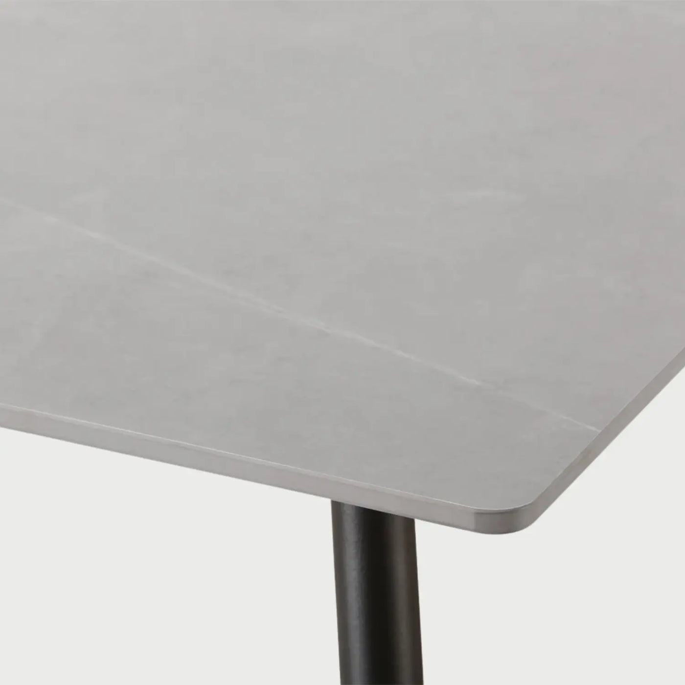 Detalle de la mesa Aroa donde se aprecia el acabado liso de la cubierta gris con vetas blancas ligeras y el ensamble de las patas metálicas oscuras, las cuales incluyen niveladores cromados en la base para proteger el piso.