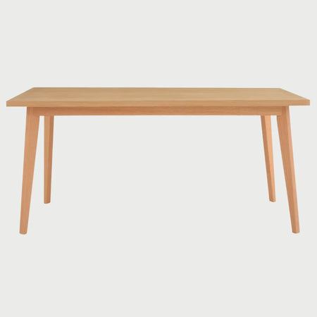 Vista frontal de la mesa de comedor Evo de 140 cm en color beige; presenta una superficie rectangular de madera clara con cuatro patas angulares de corte recto que se ensanchan ligeramente hacia la parte superior.