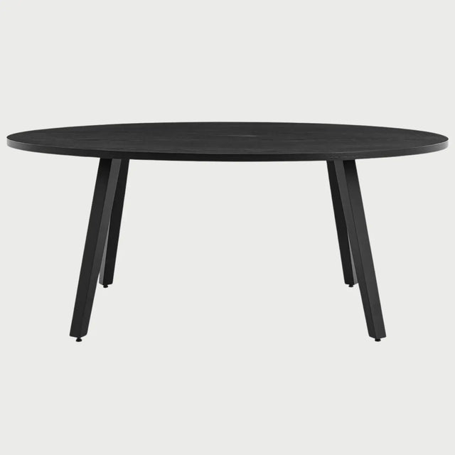 Vista frontal de la mesa de comedor ovalada Xocos en color negro; su acabado oscuro y monocromático enfatiza la silueta geométrica de las patas y la elegancia de la forma elíptica.