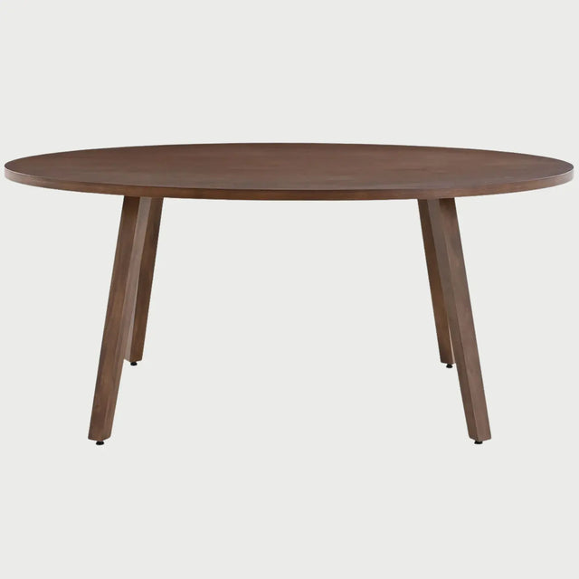 Vista frontal de la mesa de comedor ovalada Xocos en color café nogal; presenta una amplia superficie elíptica de madera con vetas naturales, apoyada sobre cuatro patas angulares robustas que ofrecen un diseño moderno y equilibrado.