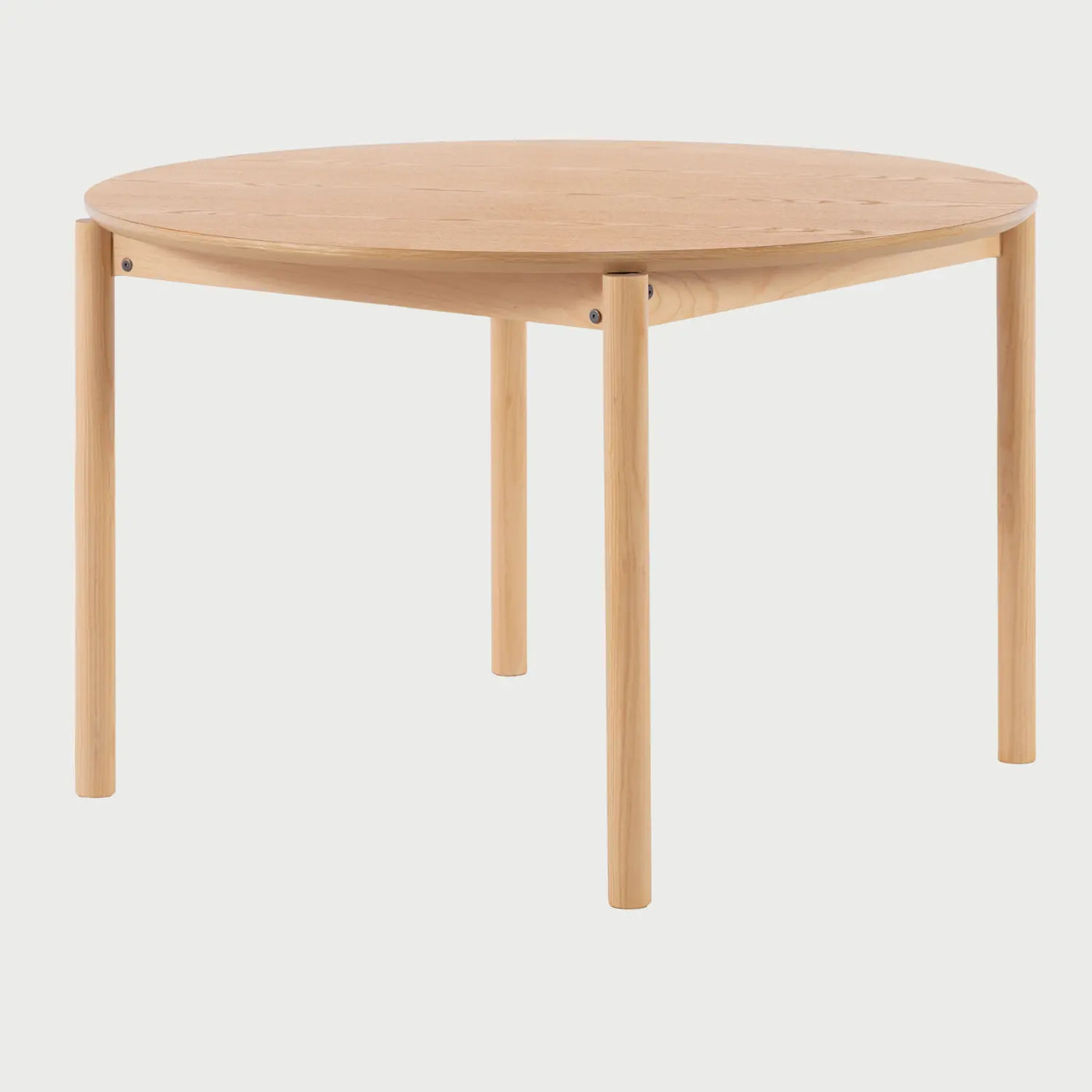 Vista de perfil de la mesa Akari donde se aprecia el grosor de la cubierta circular y el ensamblaje de las patas de madera sólida, resaltando su silueta limpia y contemporánea.