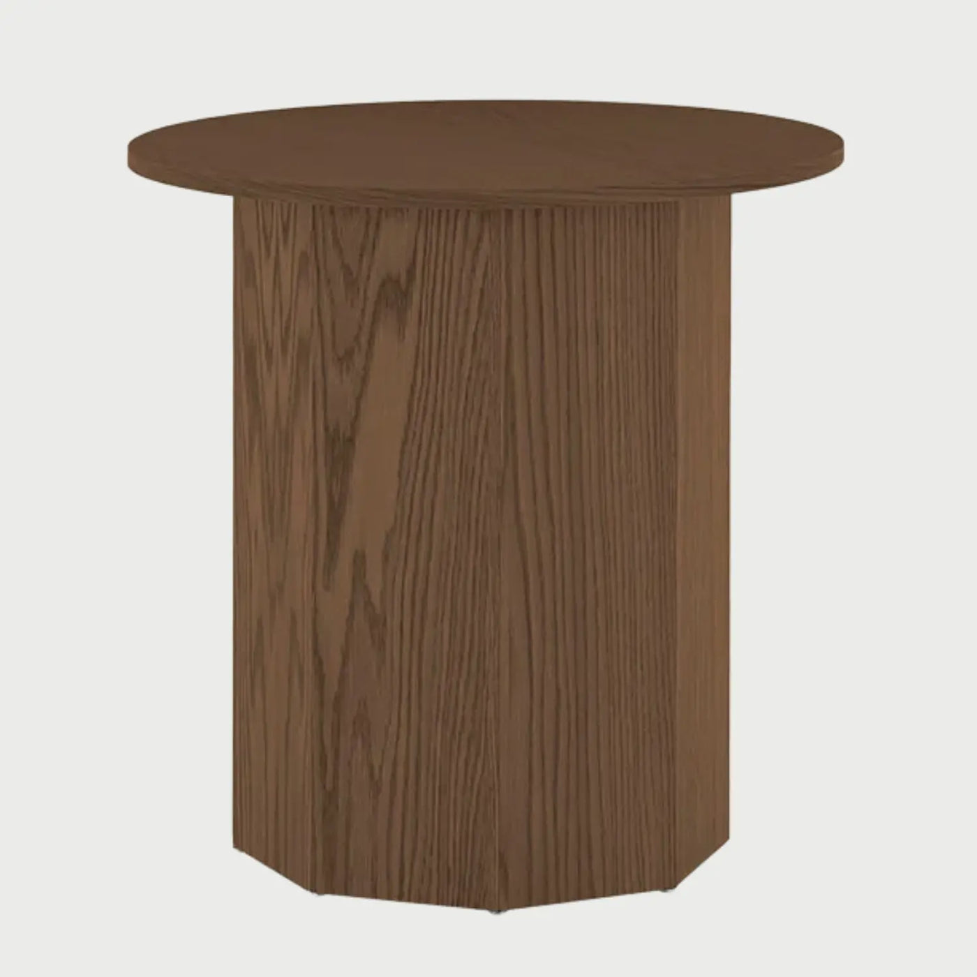 Vista frontal de la mesa lateral Aida en color nogal; presenta una superficie circular lisa que reposa sobre una base prismática hexagonal de madera con vetas verticales marcadas.