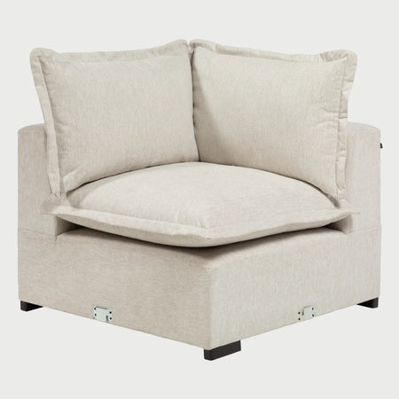 Vista frontal del módulo esquinero Emilia en color marfil; presenta una estética luminosa con grandes cojines de respaldo y patas cortas de madera oscura.