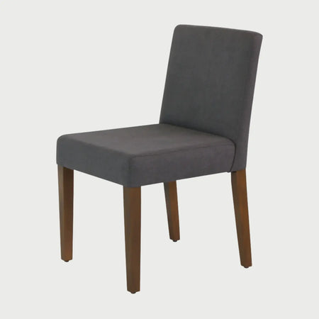 Vista frontal de la silla de comedor Talpa tapizada en tela color gris, con un respaldo de altura media y asiento acolchado integrados en una silueta cuadrada sobre patas de madera en acabado nogal.