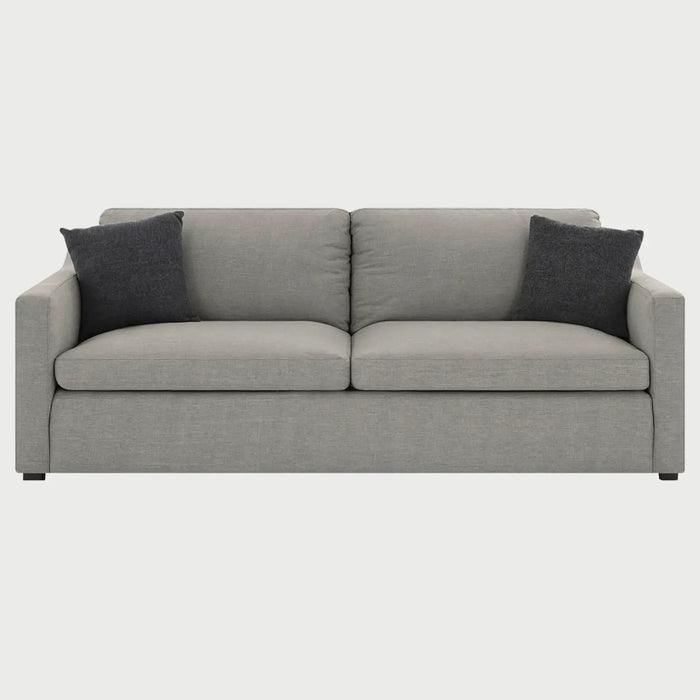 Vista frontal del sillón Marie de tres cuerpos en tela gris claro, destacando su silueta limpia y la organización proporcional de sus tres plazas con acentos textiles oscuros.