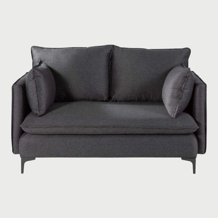 Vista frontal del sofá Cecil de dos cuerpos en color gris oscuro, resaltando la textura densa del tejido y la estructura moderna con patas metálicas que elevan la pieza del suelo.
