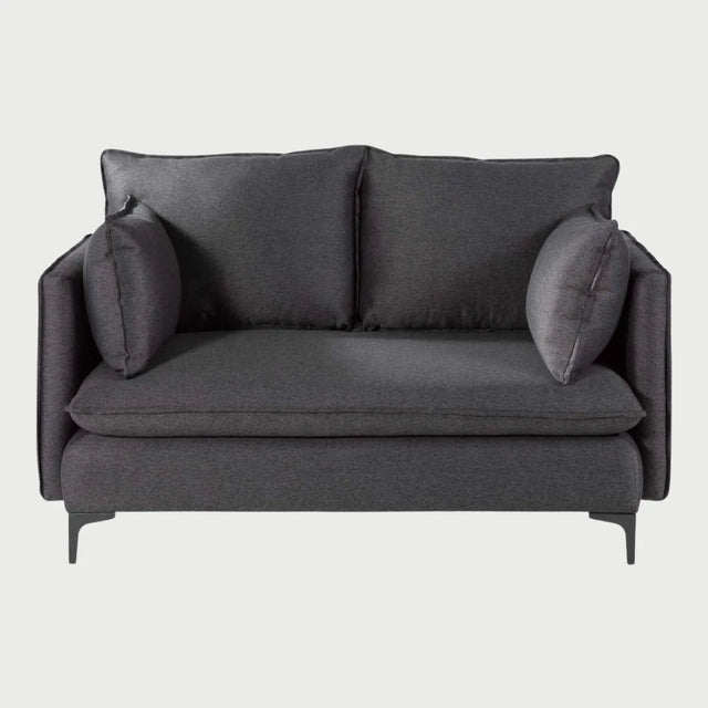 Vista frontal del sofá Cecil de dos cuerpos en color gris oscuro, resaltando la textura densa del tejido y la estructura moderna con patas metálicas que elevan la pieza del suelo.