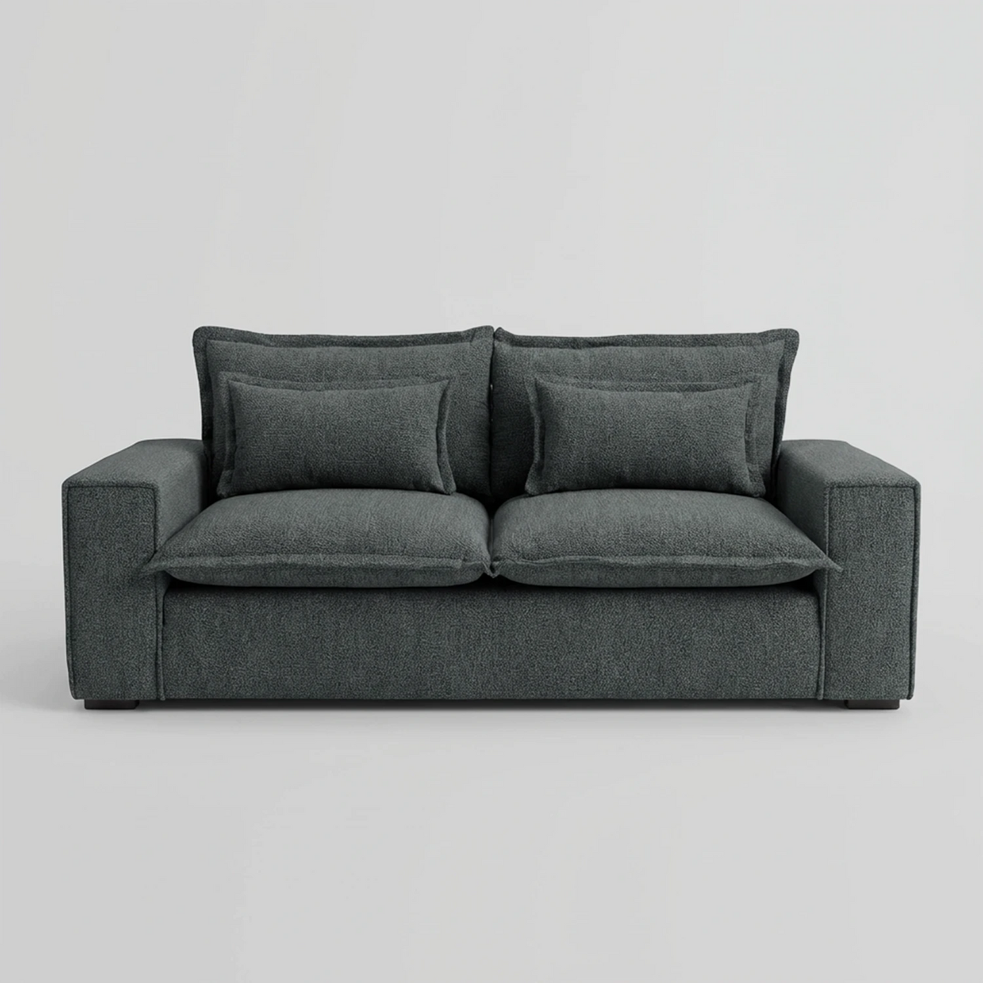 Vista frontal del sofá Emilia de dos cuerpos en color gris oscuro, mostrando su silueta robusta y cuadrada con tapizado de alta resistencia y cojines decorativos frontales.