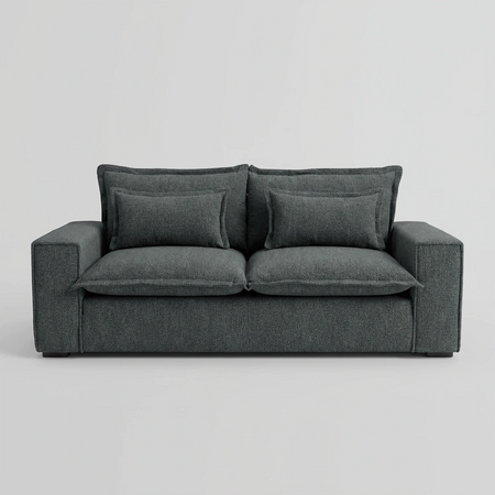 Vista frontal del sofá Emilia de dos cuerpos en color gris oscuro, mostrando su silueta robusta y cuadrada con tapizado de alta resistencia y cojines decorativos frontales.