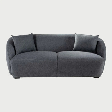 Vista frontal del sofá Kant de dos cuerpos en gris oscuro, destacando la profundidad del tono en su tejido de textura cerrada y su diseño ergonómico de formas fluidas.