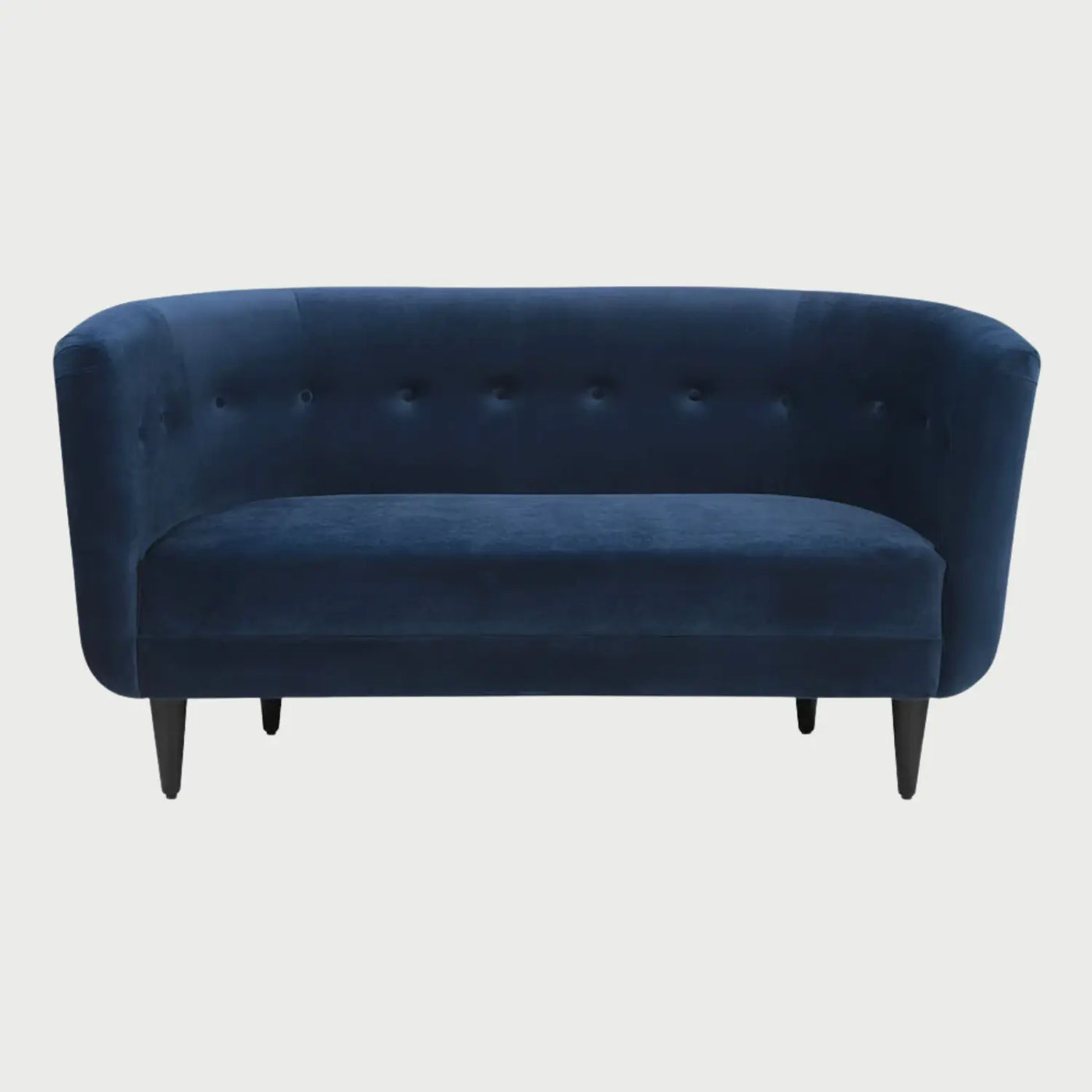 Vista frontal del sofá Tavari GAIA de dos cuerpos en terciopelo azul, con un respaldo curvo continuo que se integra a los brazos, decorado con botones tipo capitoné y patas de madera cónicas en color negro.