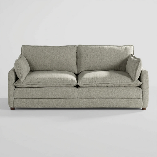 Vista frontal del sofá Andrea de tres cuerpos en color blanco, destacando su silueta robusta y la luminosidad de sus cojines de gran formato que ofrecen una apariencia acogedora.