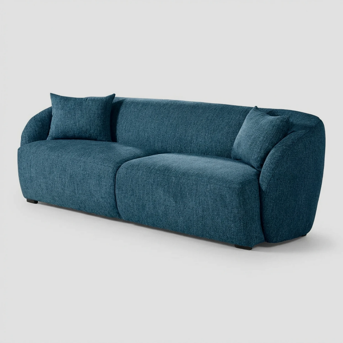 Vista lateral del sofá Kant azul de tres cuerpos, resaltando el perfil curvo continuo que une el respaldo con los descansabrazos y su estructura de bajo impacto visual.