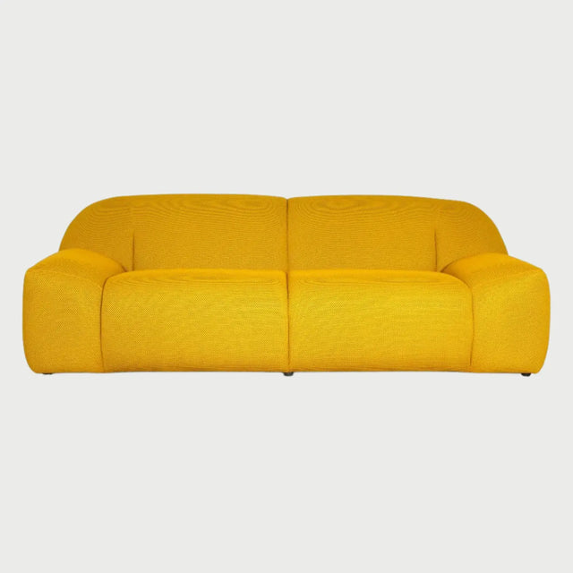 Vista frontal del sofá Marcus de tres cuerpos en color amarillo, mostrando su silueta contemporánea y acogedora en un tono vibrante que resalta sus formas redondeadas.