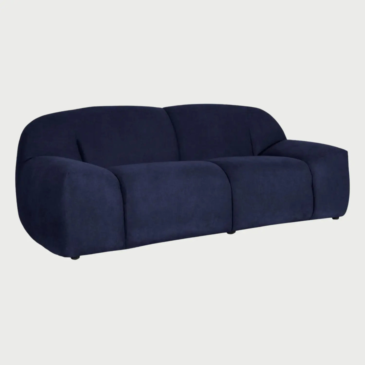 Vista lateral del sofá Marcus azul, resaltando su silueta baja y el grosor de su estructura acolchada que proporciona una estética moderna y de máximo confort.