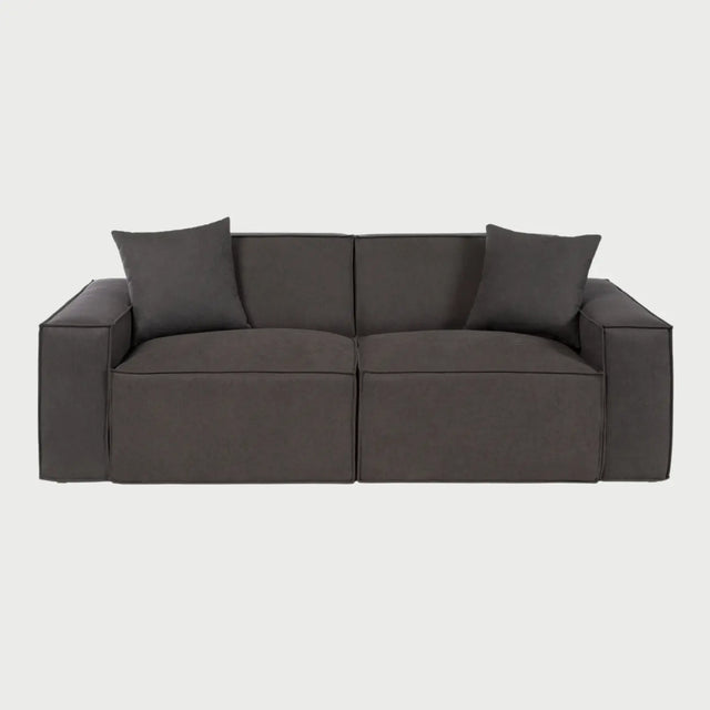 Vista frontal del sofá Otto de tres cuerpos en gris oscuro, resaltando su apariencia imponente y sofisticada con asientos profundos y una estructura de bloques que invita al descanso.