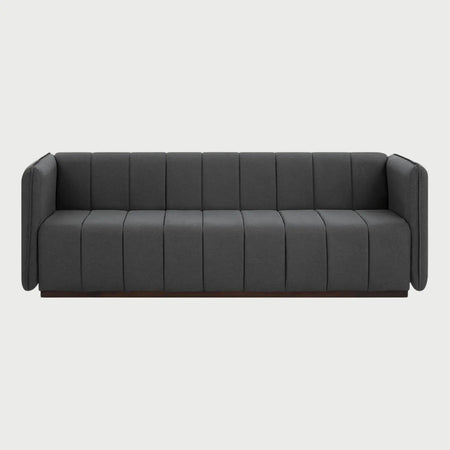 Vista frontal del sofá Porfirio de tres cuerpos en color gris oscuro, resaltando la profundidad del tono en el terciopelo y la precisión de las costuras verticales que definen su estilo contemporáneo.