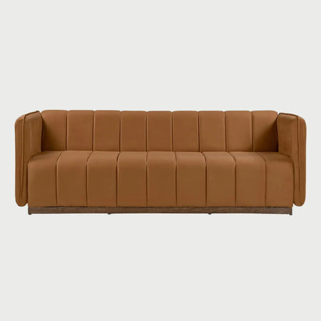 Vista frontal del sofá Porfirio GAIA de tres cuerpos en terciopelo color naranja terracota, caracterizado por un diseño acolchado con costuras verticales uniformes en respaldo y asiento, brazos integrados y una base de madera sólida de perfil bajo.