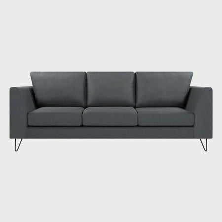 Vista frontal del sofá Yoco de tres cuerpos en color gris oscuro, resaltando el contraste entre el tapizado profundo y las estilizadas patas metálicas negras.