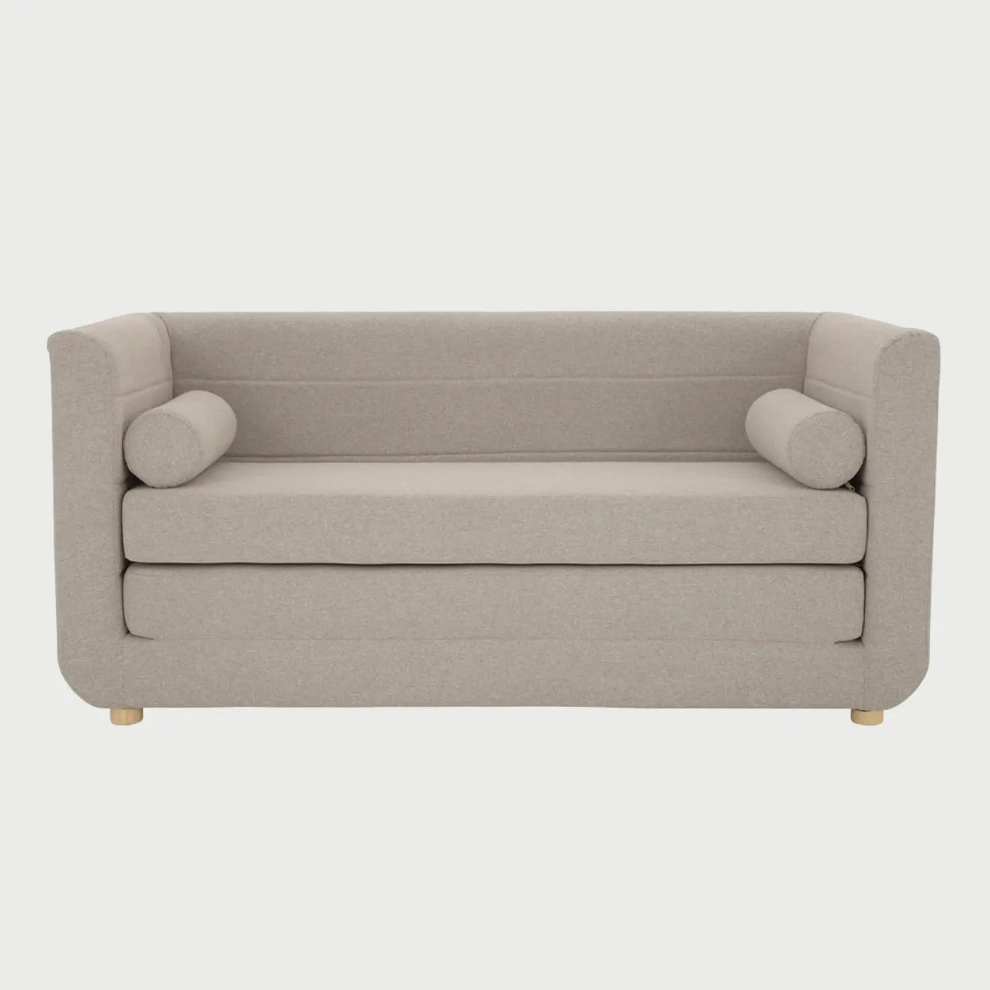 Vista frontal del sofá cama Basil de GAIA en tela amarilla, con un diseño de respaldo bajo y brazos integrados de altura uniforme, asiento de doble capa y dos cojines decorativos cilíndricos en los extremos.