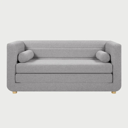 Vista frontal del sofá cama Basil en color gris neutro, resaltando la versatilidad de su diseño para espacios multifuncionales y el detalle de sus costuras horizontales en el respaldo.