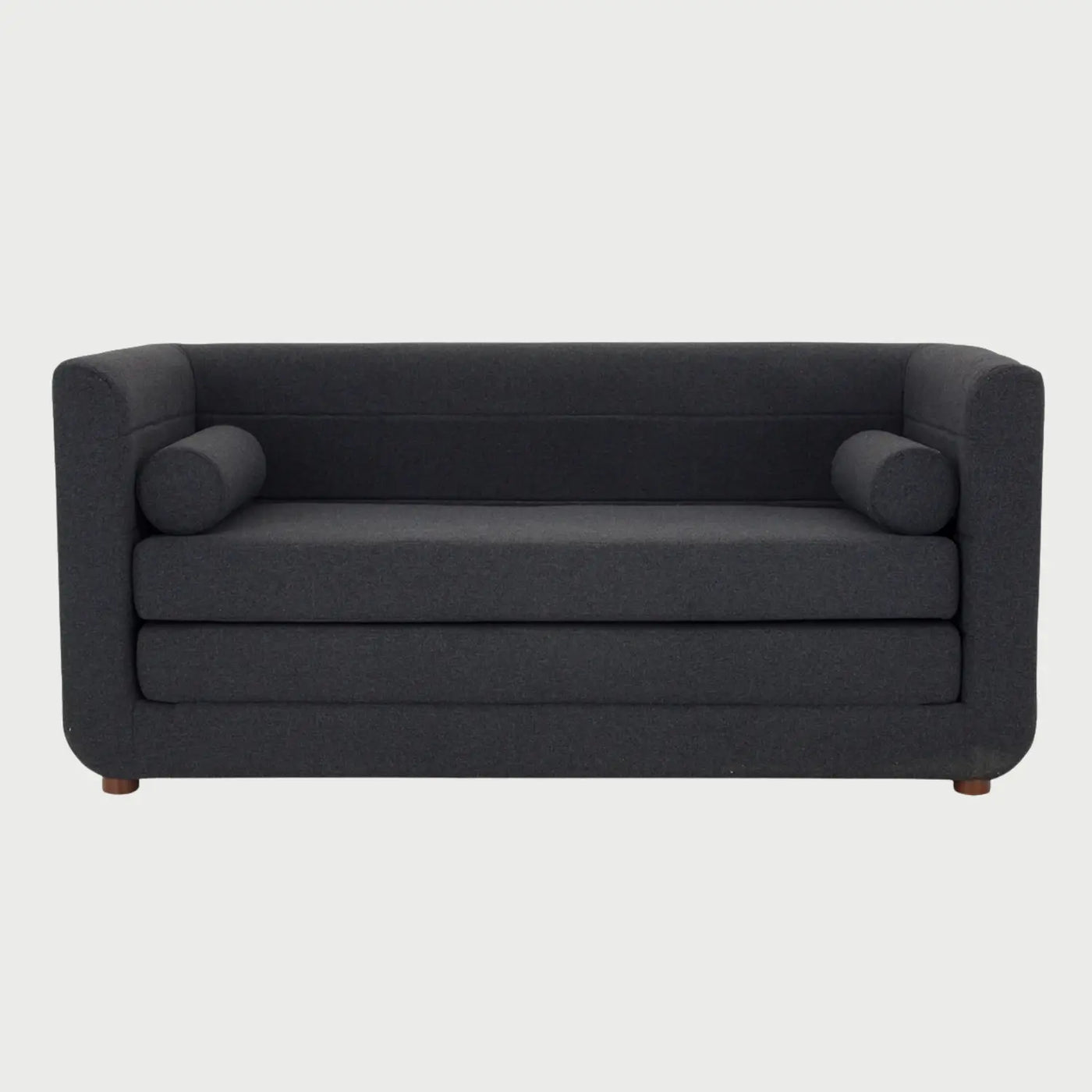 Vista frontal del sofá cama Basil en color gris oscuro, destacando la sobriedad del textil en combinación con las patas de madera en acabado nogal.