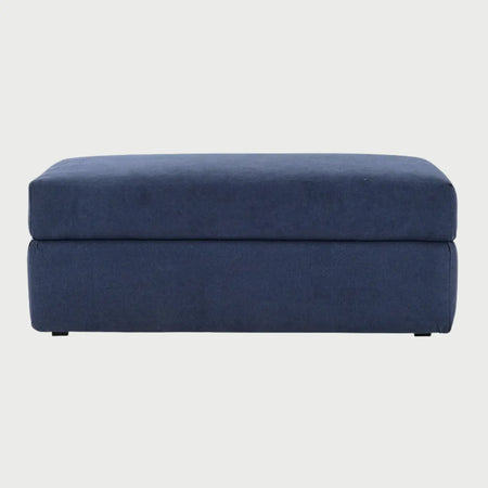 Vista frontal del taburete Amil tapizado en tela premium color azul marino, con un diseño rectangular de líneas limpias y estructura acolchada compacta.