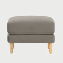 Vista frontal del taburete Levanto en color beige, con un diseño de cojín superior acolchado de bordes rectos y base elevada sobre patas de madera clara en acabado encino.