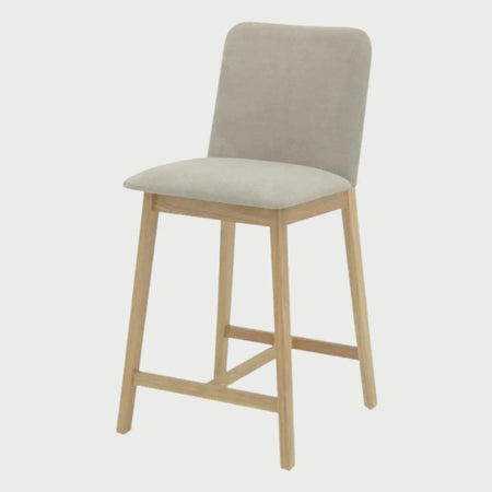 Vista lateral del banco alto Ledel beige, mostrando el perfil delgado del respaldo y la inclinación de las patas de madera clara que brindan una postura ergonómica para barras.