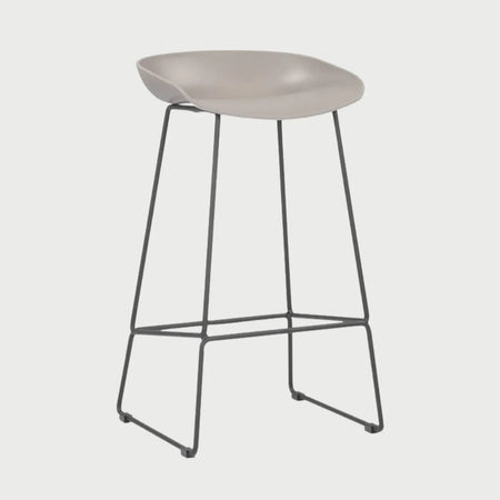 Vista lateral del banco alto Morel beige, mostrando la ligera curvatura del asiento diseñada para el confort y la estabilidad de su base metálica de líneas finas.