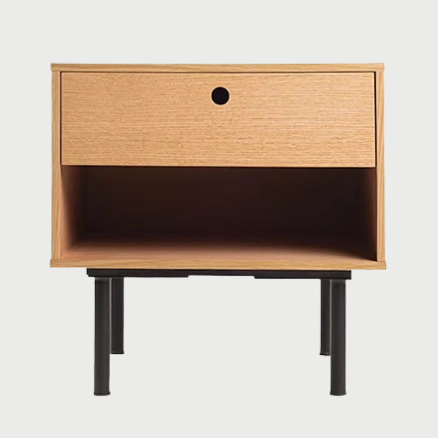Vista frontal del buró Tijuana en acabado encino beige, que presenta un cajón superior con tirador circular tipo uñero y un nicho inferior abierto, soportado por una base metálica de patas cilíndricas negras.