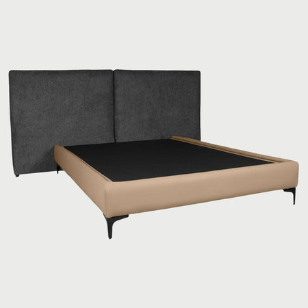 Vista lateral de la cama Blake; muestra el diseño de perfil bajo de la base acolchada beige y la profundidad de la cabecera gris, resaltando una silueta limpia y moderna que se eleva ligeramente sobre patas metálicas oscuras.