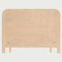 Vista posterior de la cama Iki; muestra el reverso de la cabecera de madera y la solidez de los ensambles que sostienen el panel acolchado beige, resaltando la calidad de la ebanistería.