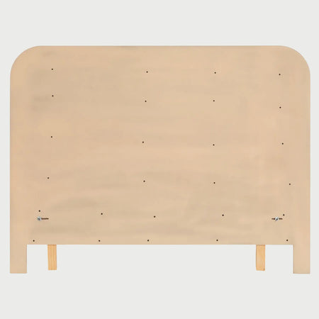 Vista posterior de la cama Iki; muestra el reverso de la cabecera de madera y la solidez de los ensambles que sostienen el panel acolchado beige, resaltando la calidad de la ebanistería.