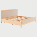 Vista en perspectiva de la cama Iki; destaca la fluidez de sus líneas redondeadas en madera clara y el diseño de perfil bajo que descansa sobre una base sólida, evocando una estética minimalista y serena.