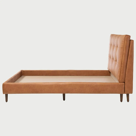 Vista lateral de la cama Landero; muestra el grosor del marco perimetral tapizado en café claro y las patas cilíndricas de madera que elevan la estructura de perfil bajo.