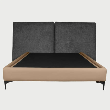 Vista frontal de la cama matrimonial Blake; presenta una cabecera alta dividida en dos paneles acolchados de color gris oscuro, que contrasta con una base de perfil bajo tapizada en color beige arena y patas metálicas negras de diseño angular.