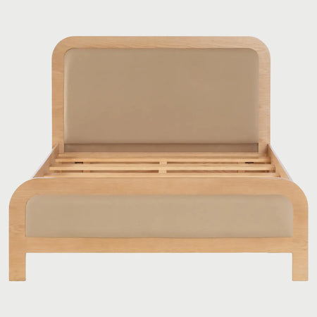 Vista frontal de la cama matrimonial Iki; presenta una estructura de madera clara con bordes curvos y paneles acolchados en color beige integrados tanto en la cabecera como en el pie de cama para un acabado suave y armónico.