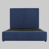 Vista frontal de la cama matrimonial Raquel; presenta una imponente cabecera alta y rectangular tapizada en terciopelo azul profundo que se integra con una base de perfil bajo del mismo tono, creando una silueta moderna y sofisticada.