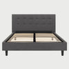 Vista frontal de la cama Queen Size Volpi; destaca una cabecera alta tapizada en tela gris oscuro con un elegante diseño de capitonado cuadrado que aporta textura y un estilo contemporáneo al dormitorio.
