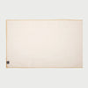 Vista frontal extendida del camino de mesa Cristina en color blanco roto o marfil; presenta una superficie rectangular de tela lisa con un distintivo borde perimetral en fibra natural de yute color arena.